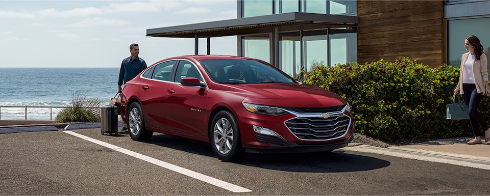 Des gens mettent des valises dans la Chevrolet Malibu 2023.