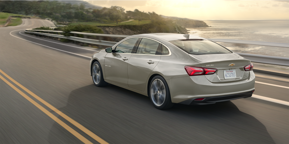 La Chevrolet Malibu 2024 en gris minéral métallisé en mouvement sur la route au bord de la mer.