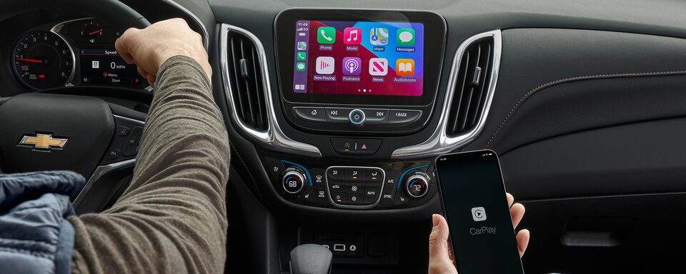 A couple uses the Apple CarPlay feature to enhance their 2023 Chevrolet Equinox experience.