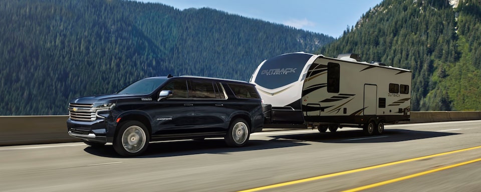 Chevrolet Suburban 2023 qui remorque une caravane sur la route.