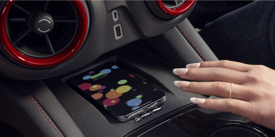A woman reaching for her smartphone on the wireless charging station.