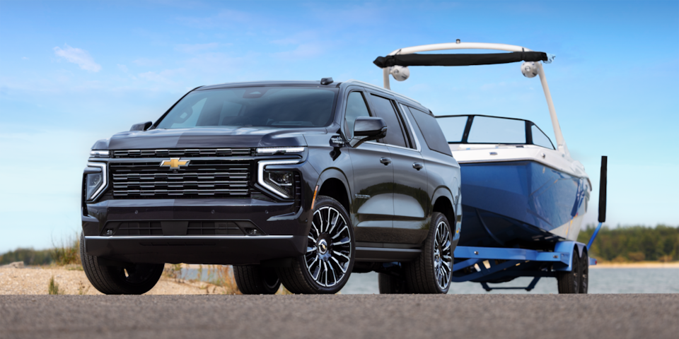 Front three-quarters view of the 2025 Chevrolet Suburban towing a boat by the beach.