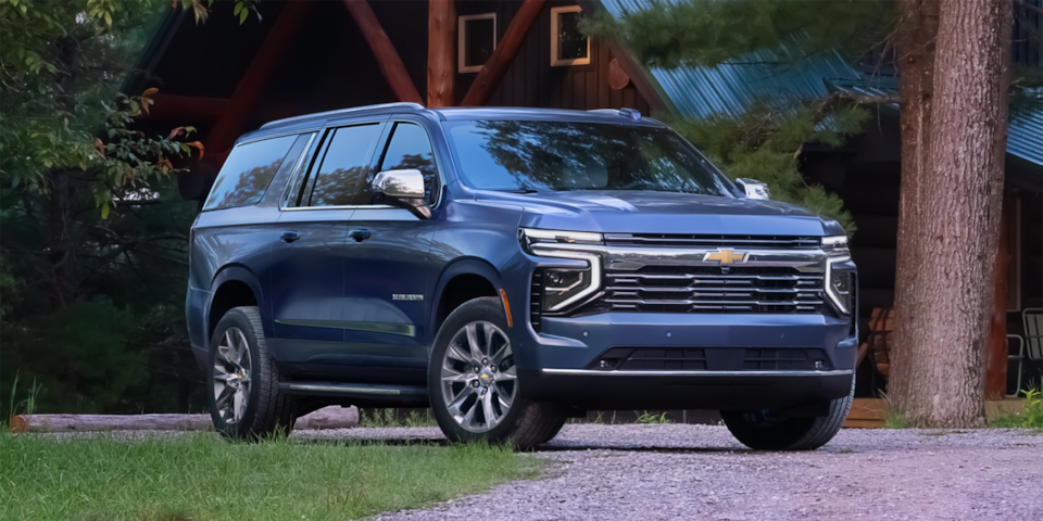 Front three-quarters view of the 2025 Chevrolet Suburban partially parked on a gravel road.