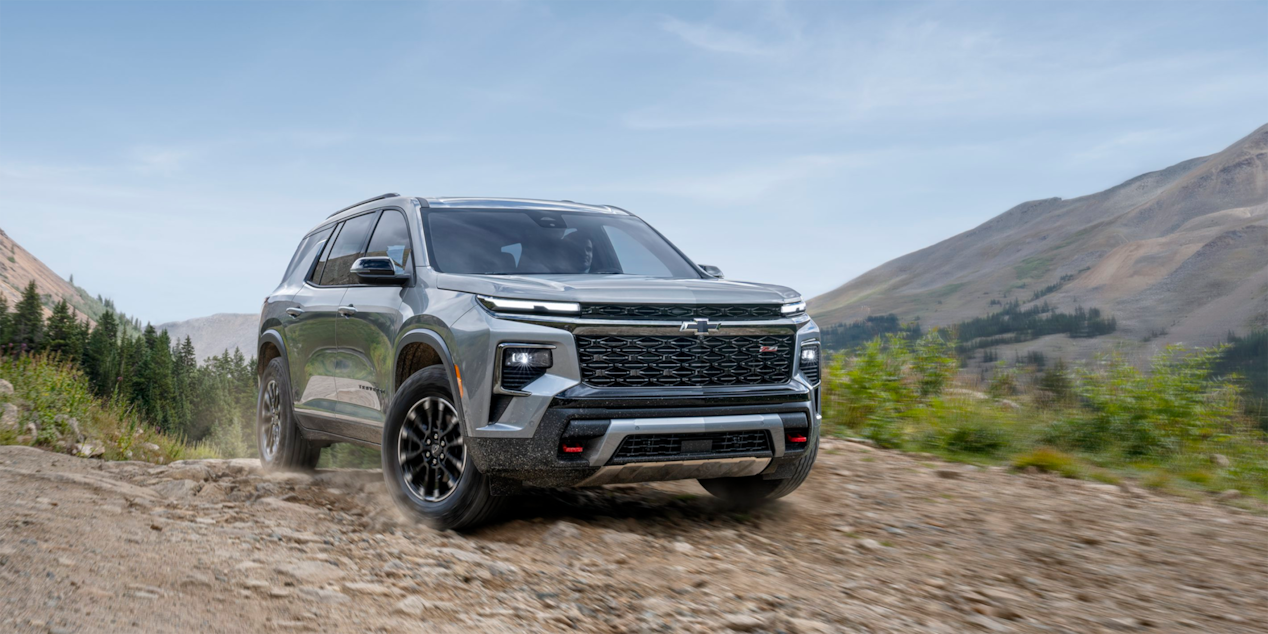 Vue latérale avant du VUS Chevrolet Traverse 2025 en mouvement sur un chemin de terre.