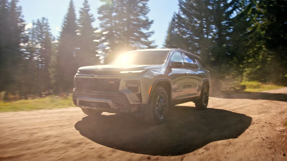 Vue latérale avant du VUS Chevrolet Traverse 2025 en mouvement seul sur un chemin de terre.