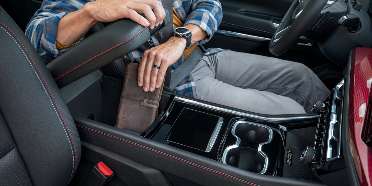 Une personne range un calepin dans le compartiment de rangement de la rangée avant du VUS Chevrolet Traverse 2025.