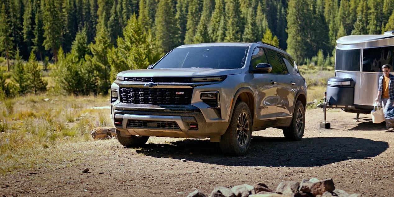 Vue latérale avant du VUS Chevrolet Traverse 2025 qui tire une remorque sur un chemin de terre.