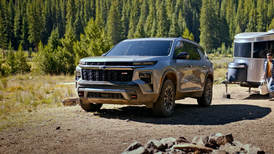 Vue latérale avant du VUS Chevrolet Traverse 2025 qui tire une remorque sur un chemin de terre.
