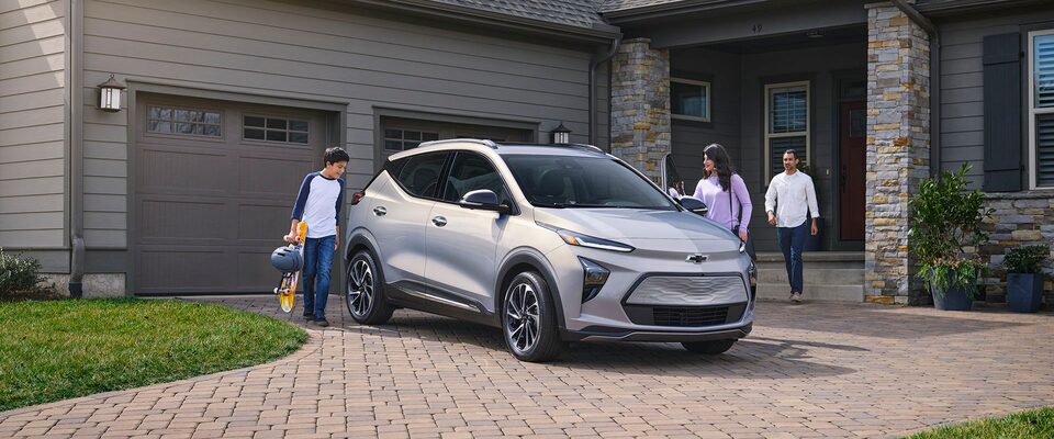 Une famille s’apprête à monter dans un VÉ Chevrolet dans l’entrée.