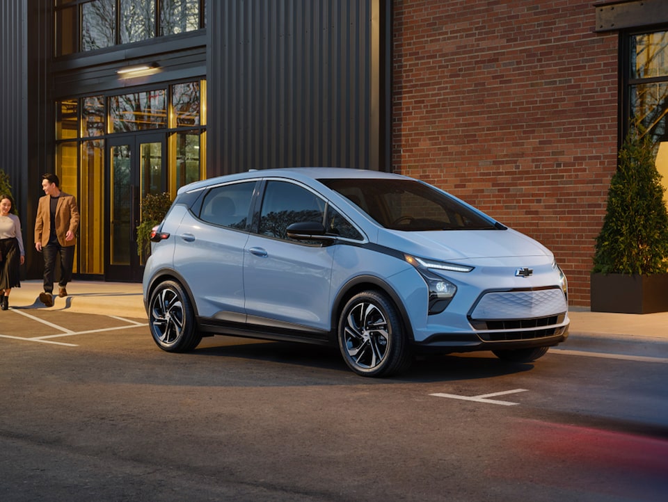 Une Chevrolet Bolt EV stationnée devant un bâtiment.