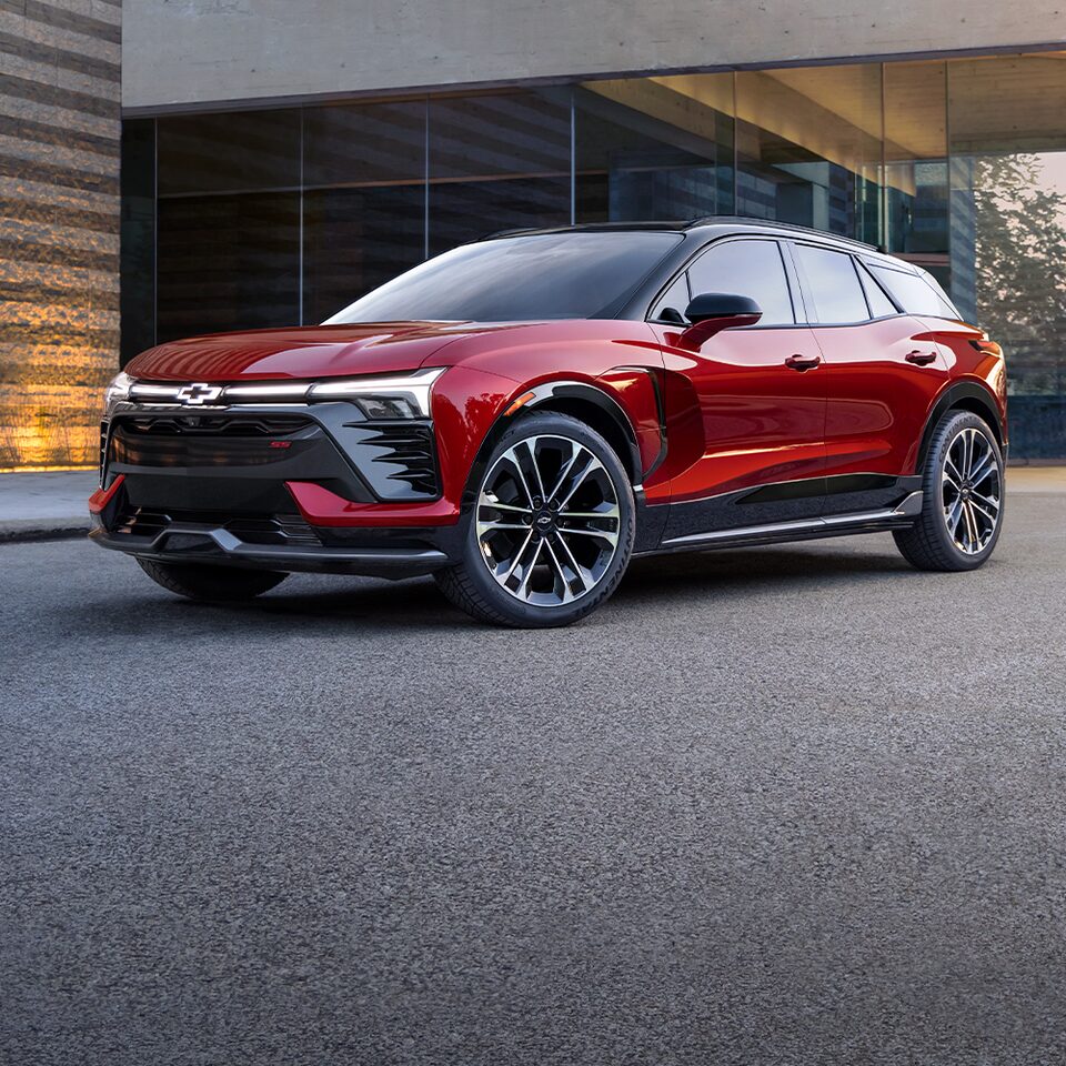 Un VÉ Chevrolet rouge stationné dans la rue devant un bâtiment.