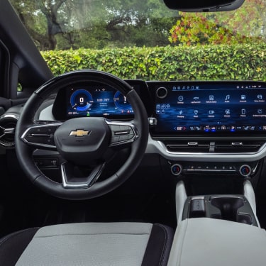 Interior Driver Seat View of the Chevrolet Equinox EV While Outlooking a Lake Surrounded by Trees