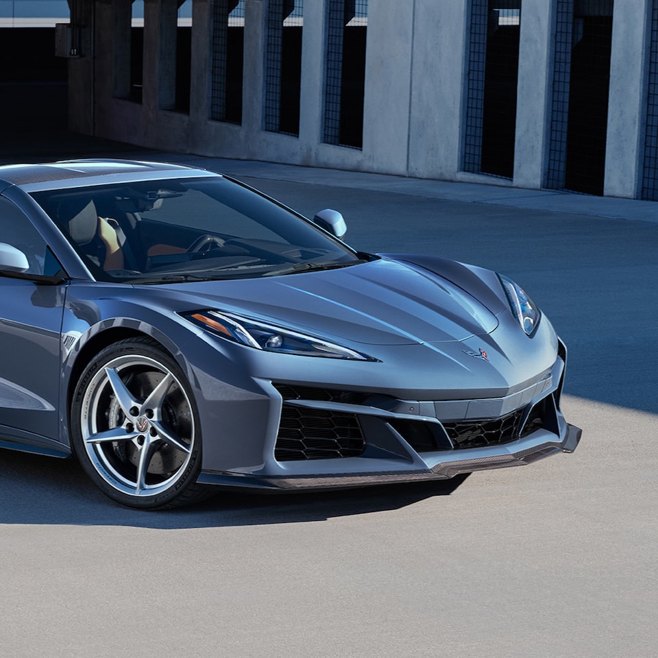 Vue rapprochée de l’avant et du capot d’une Chevrolet Corvette E-Ray 2024 stationnée près d’un bâtiment.