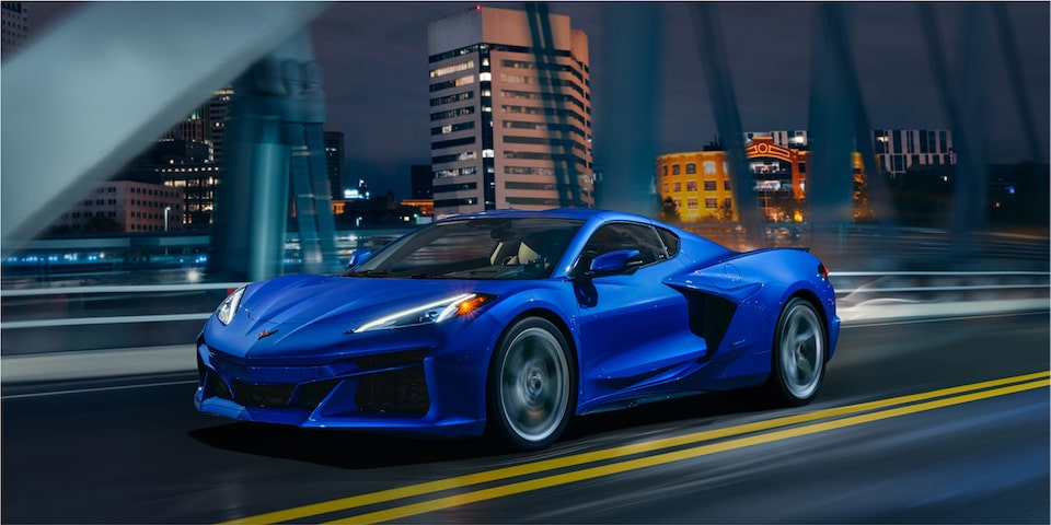 La Chevrolet Corvette E-Ray 2024 sur un pont en ville la nuit.