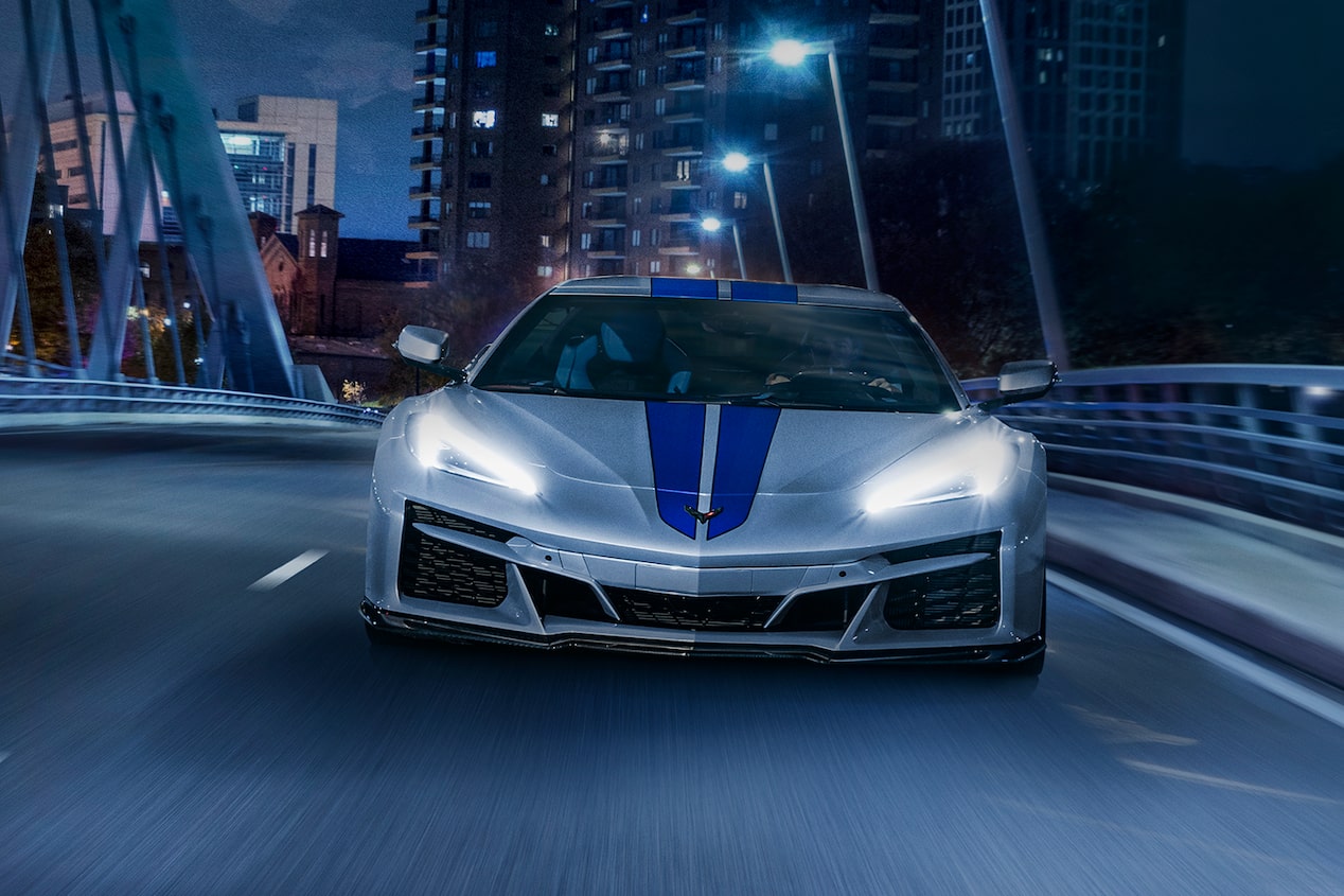 The 2024 Chevrolet Corvette E-Ray head-on driving on city bridge at night with lights on.
