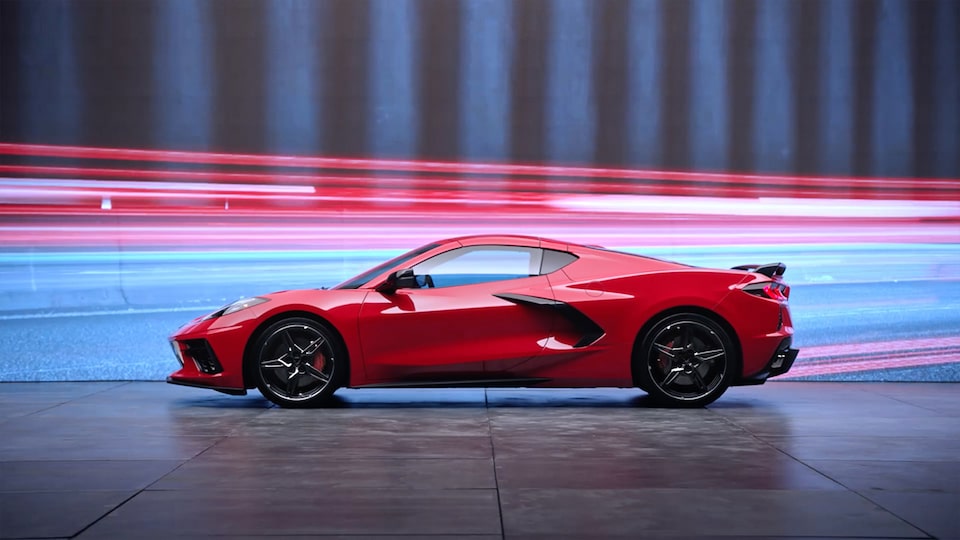 Side View of a 2025 Chevrolet Corvette Stingray driving with bright lights flashing in the surroundings.