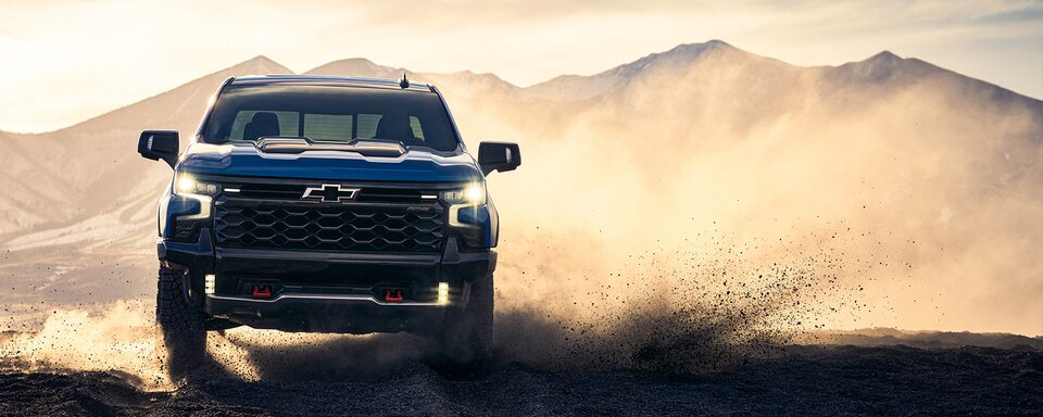Front view of the 2022 Chevrolet Silverado 1500 pickup truck driving on dusty terrain.