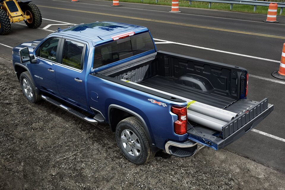 Chevrolet Silverado HD 2023 qui utilise le hayon Multi-Flex pour transporter des tuyaux en PVC de façon sécuritaire.