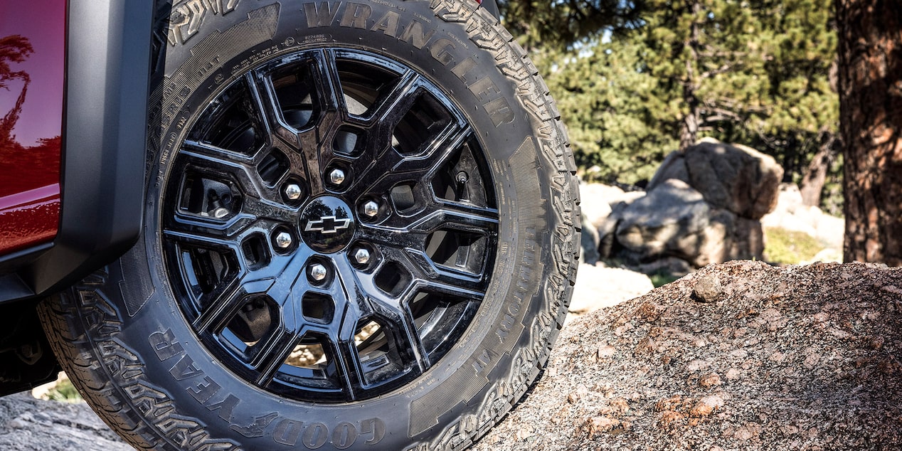 Vue rapprochée des roues du Chevrolet Colorado 2025 stationné sur un terrain poussiéreux.