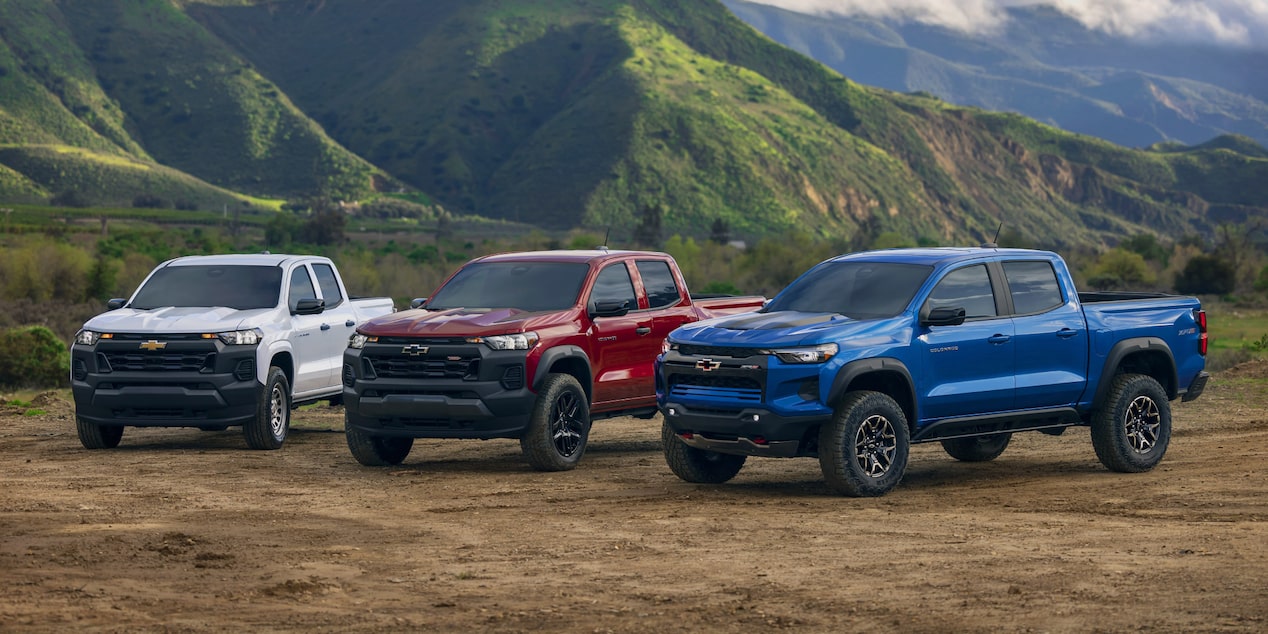 Trois camions Chevrolet Colorado stationnés à côté d'une montagne.