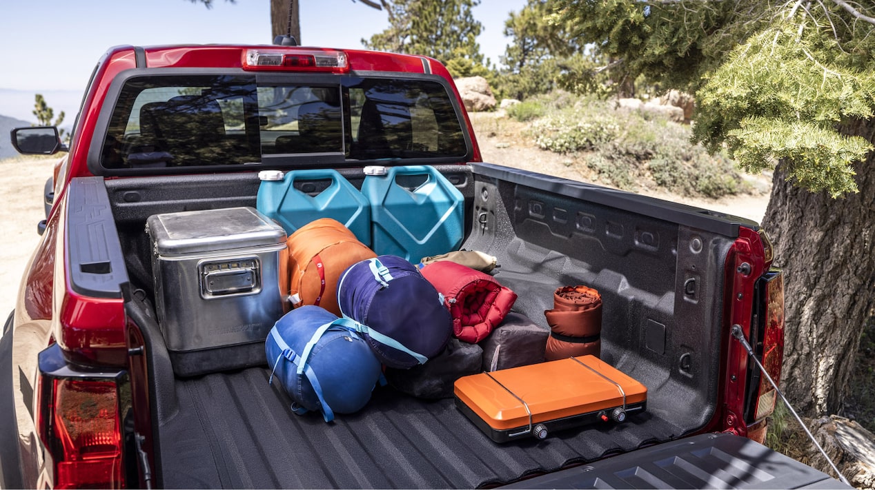 Vue arrière de la caisse d’un Chevrolet Colorado 2025 qui se fait charger d’équipements de camping et de voyage.