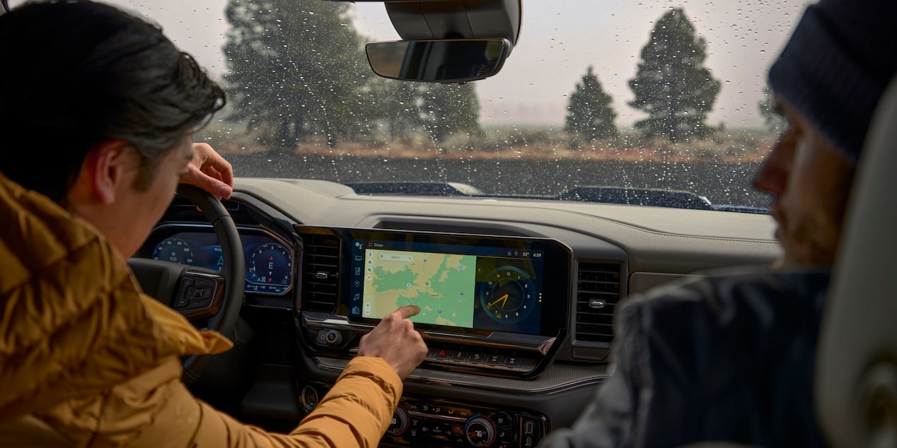 Two people in the front seats of the 2025 Chevrolet Silverado LD viewing the map on the display screen.