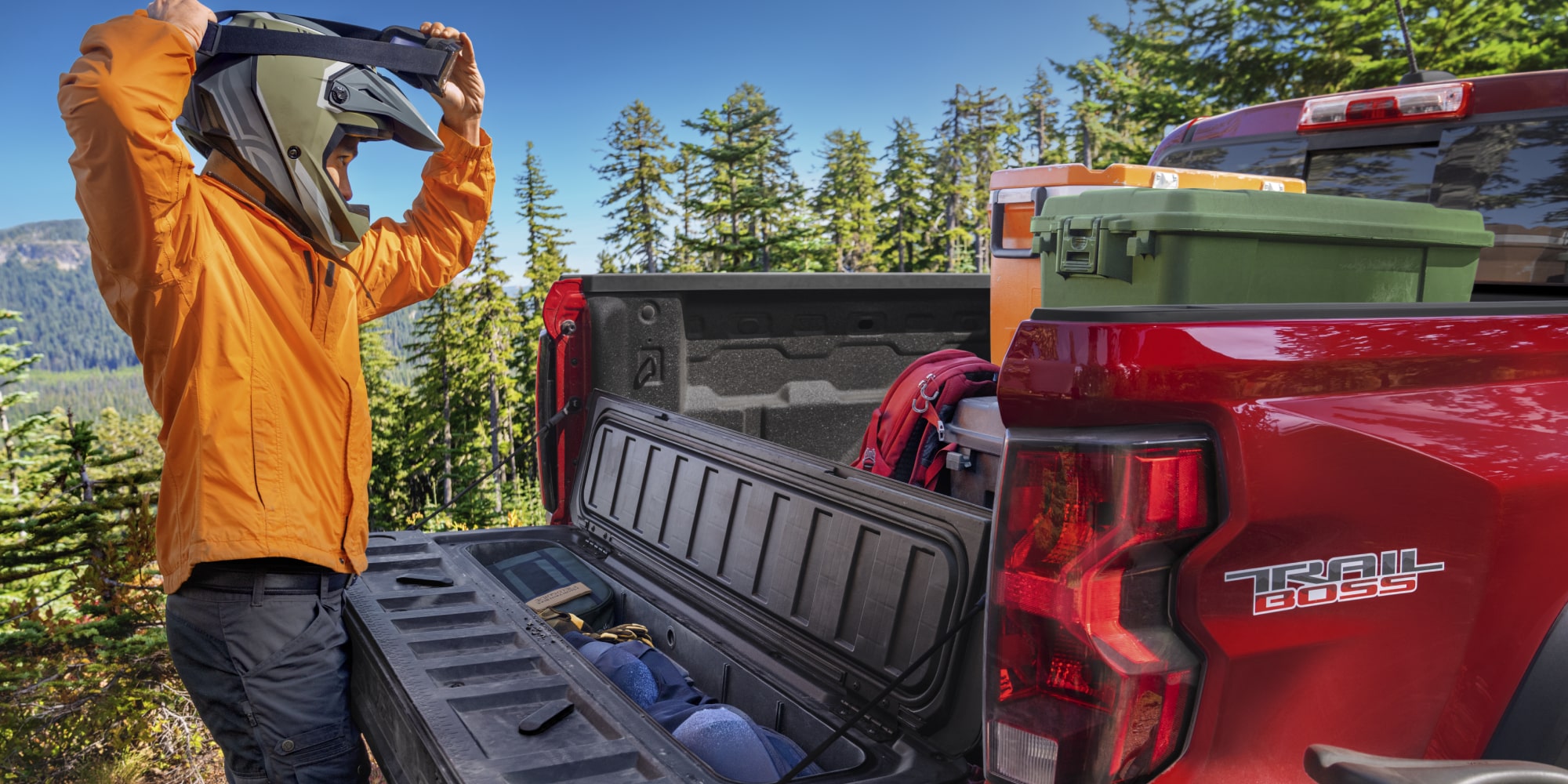 A Person with Helmet Is Checking the Cargo of a Red 2026 Chevrolet Colorado Pickup Truck.