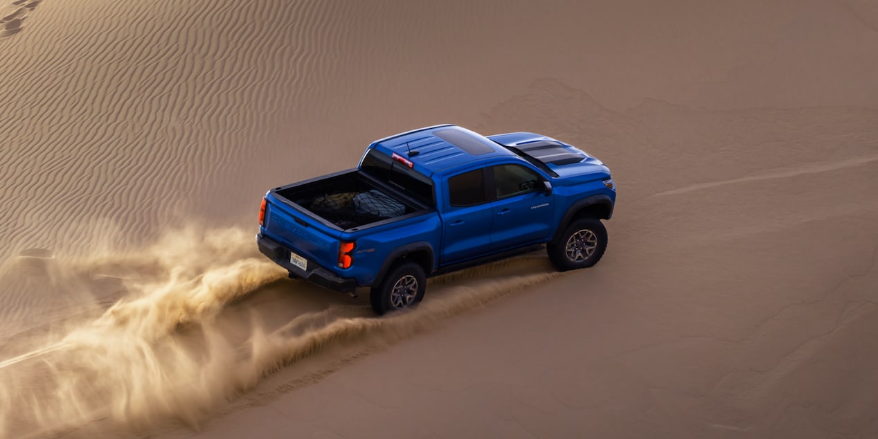 Bird's eye view of a blue Chevrolet ZR2 off-road truck driving through a Sandy Terrain.