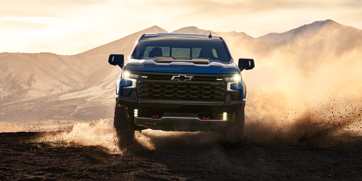 Front view of a Blue Chevrolet ZR2 off-road truck Driving in Desert at Sunset.