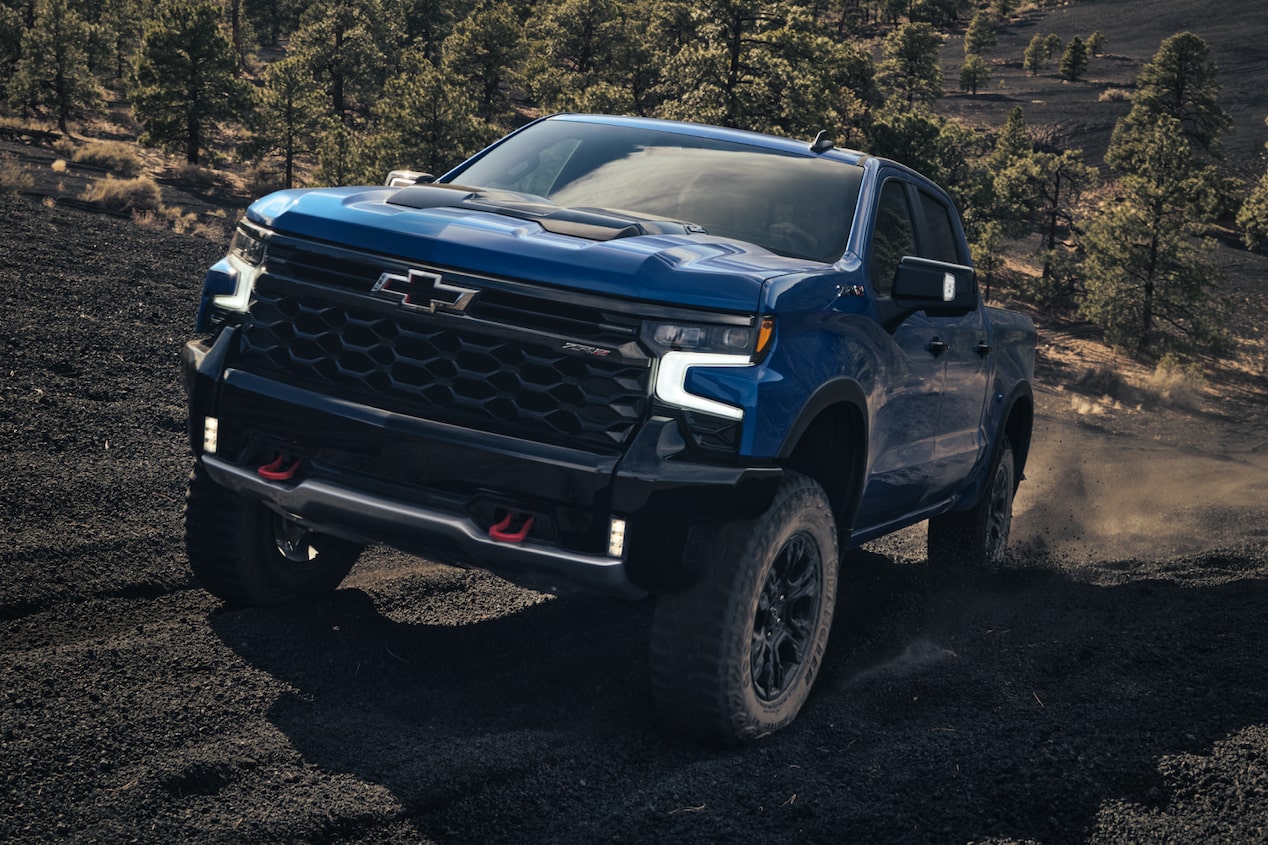 Front-side view of a Blue Chevrolet Silverado ZR2 off-road truck driving quickly on a rugged terrain.