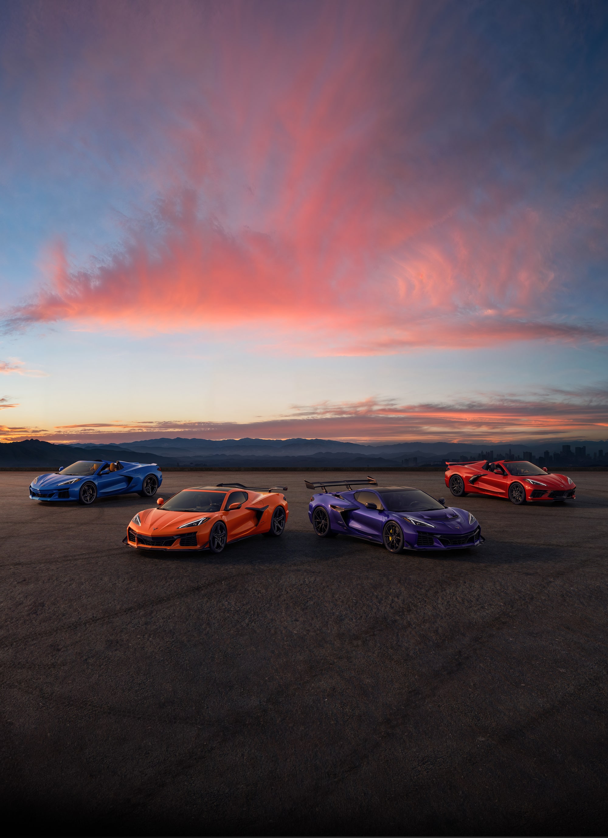 A lineup of Chevrolet Corvette vehicles parked outdoors during sunset.