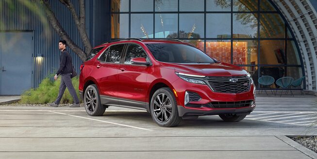 2022 Chevrolet Equinox Compact SUV in Red Parked In Front of Glass Building: Front View.