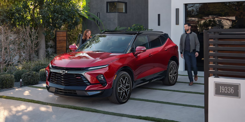 Two people about to enter a Chevrolet SUV parked near a house.