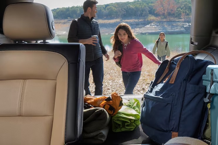 A family stowing their bags on the trunk of a Chevrolet SUV.