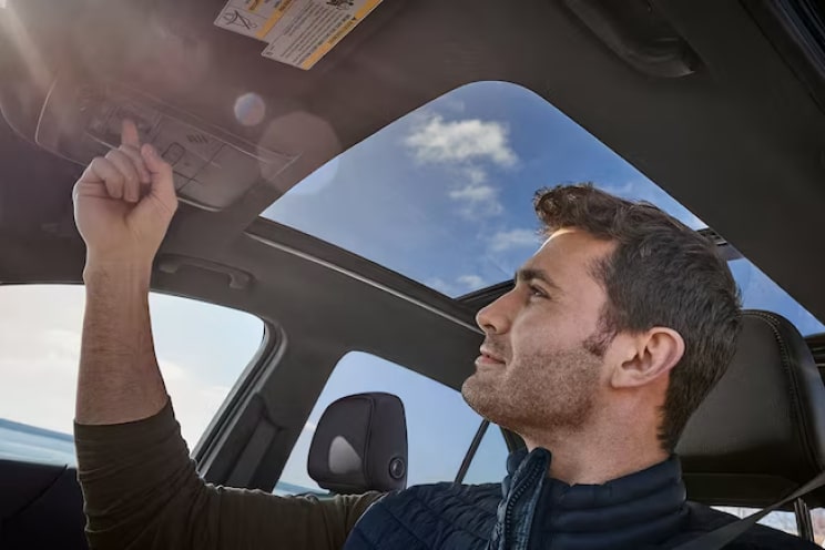 A driver pressing a button inside a Chevrolet SUV.