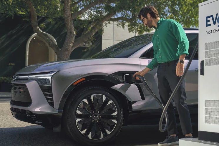 A person charging a Chevrolet Electric SUV on a public charging station.