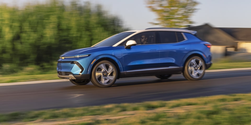 Side view of a Chevrolet Blazer EV electric SUV driving fast in the neighborhood.