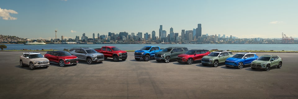 A lineup of ten Chevrolet SUVs with a city in the background.