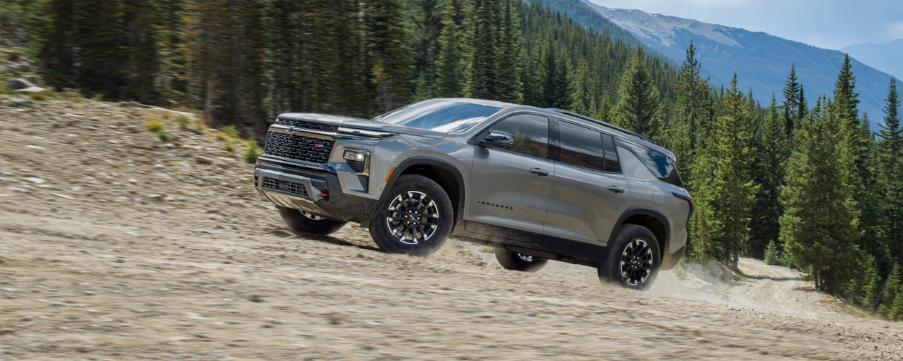 VUS Chevrolet Traverse 2025 en mouvement sur un chemin de terre bordé d’arbres.