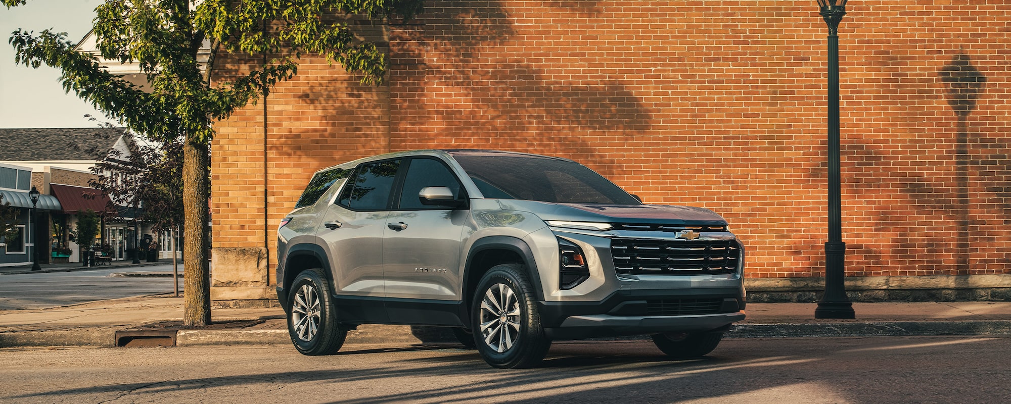 Front-side view of the 2026 Chevrolet Equinox driving past a red brick wall.