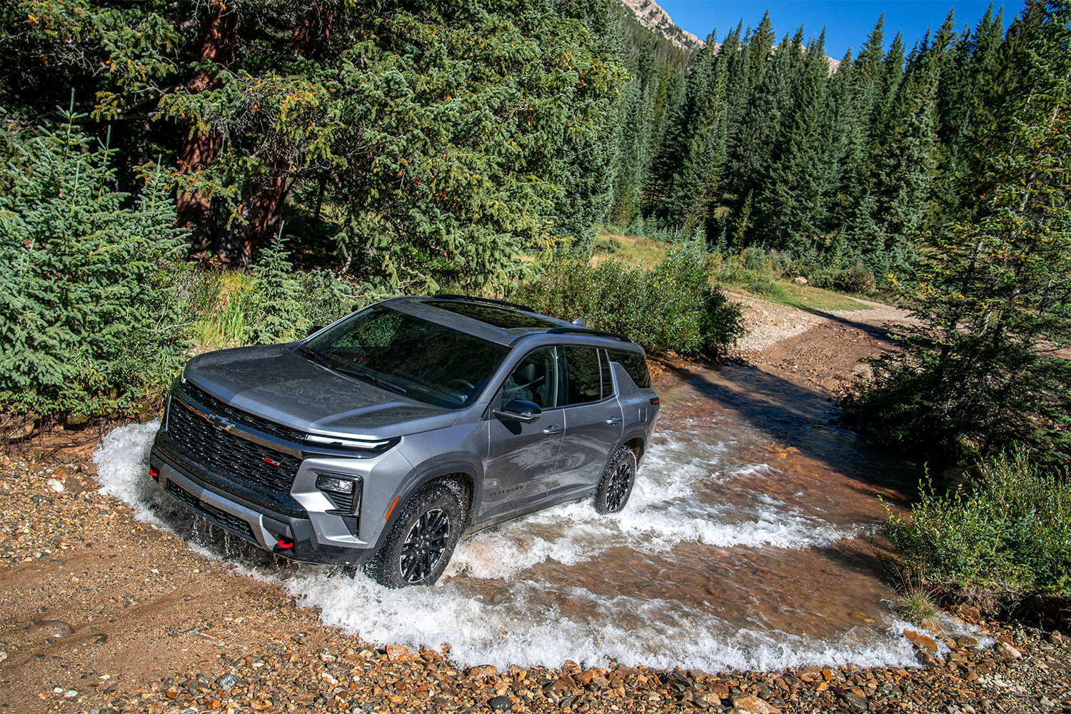 2026 Chevrolet Traverse Driving Through a Puddle of Water in the Woods.