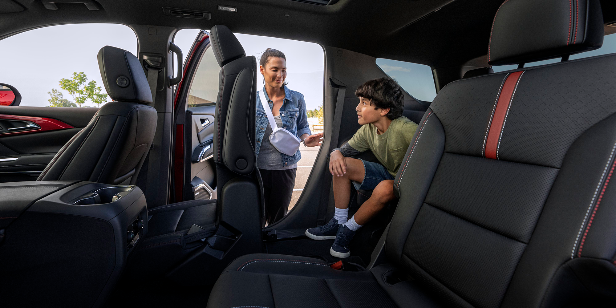 A Person Folding Down the Second Row Seats For Their Child to Exit the Third Row in the 2026 Chevrolet Traverse.