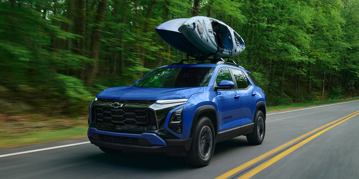 2027 Chevrolet Equinox driving alone on a tree-lined road.