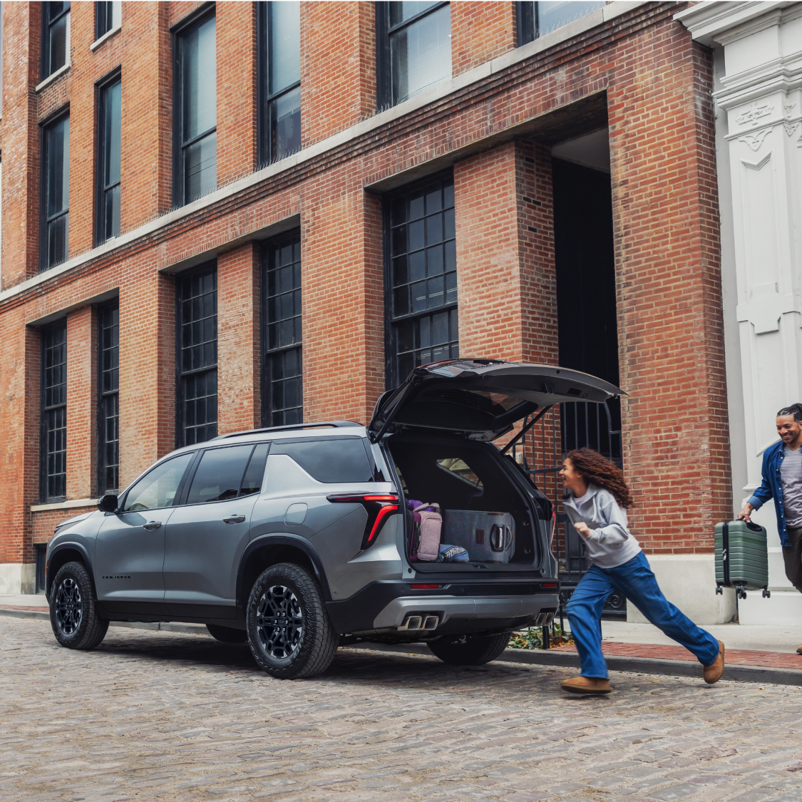 Une personne rangeant des sacs dans le coffre d’une Chevrolet Traverse 2027.