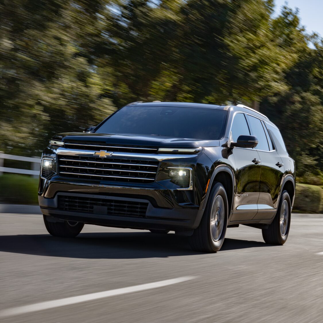 Vue de face de la Chevrolet Traverse 2027 roulant sur une route bordée d’arbres.