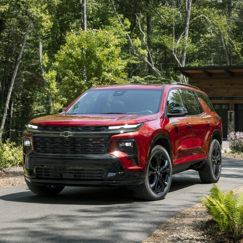 Vue de face de la Chevrolet Traverse 2027 stationnée sur un trottoir bordé d’arbres.