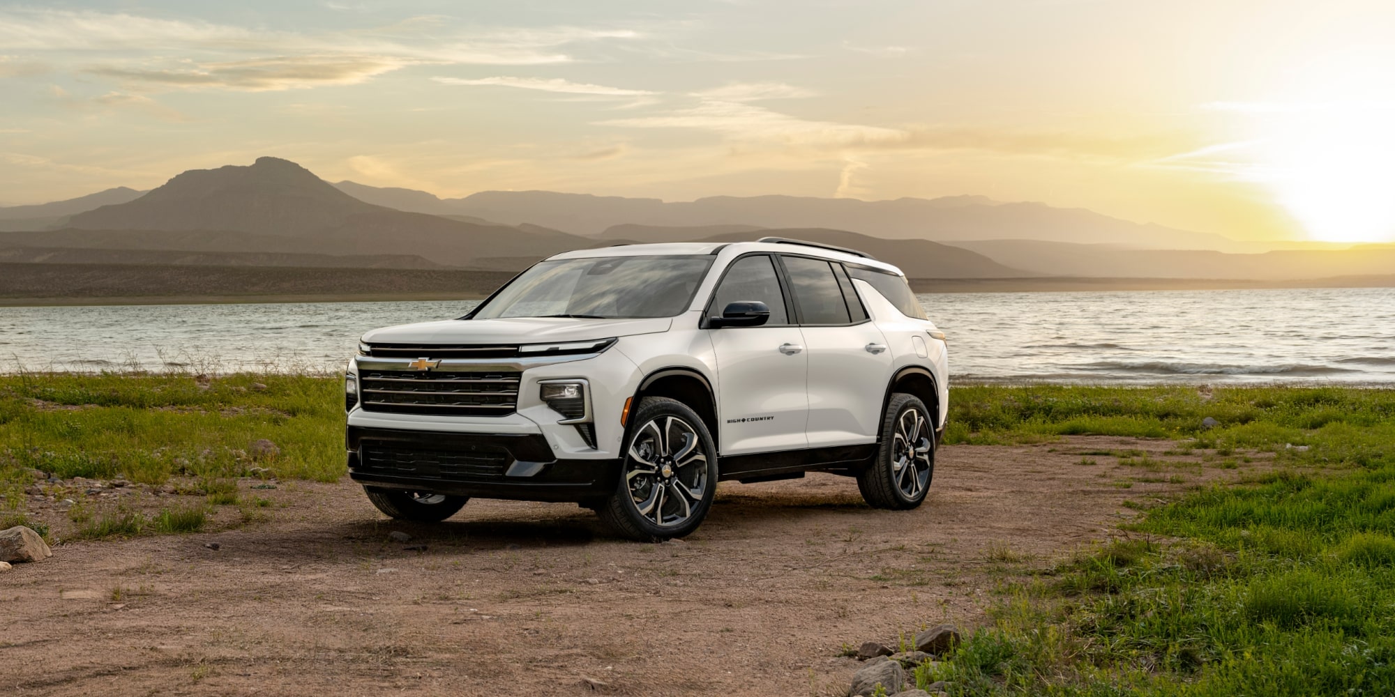 La Chevrolet Traverse High Country 2027 est stationnée sur un sentier de terre près du lac.