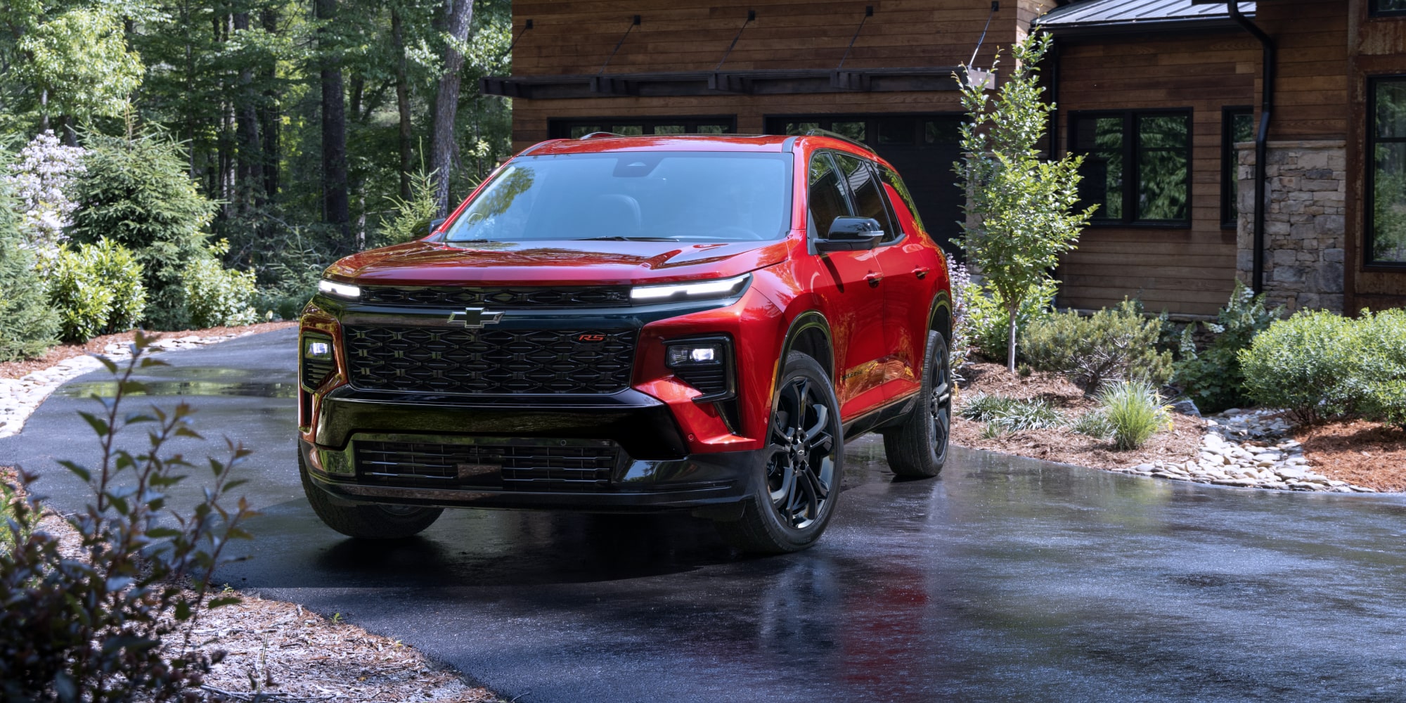 Vue de face d’une Chevrolet Traverse 2027 stationnée devant un pavillon forestier.