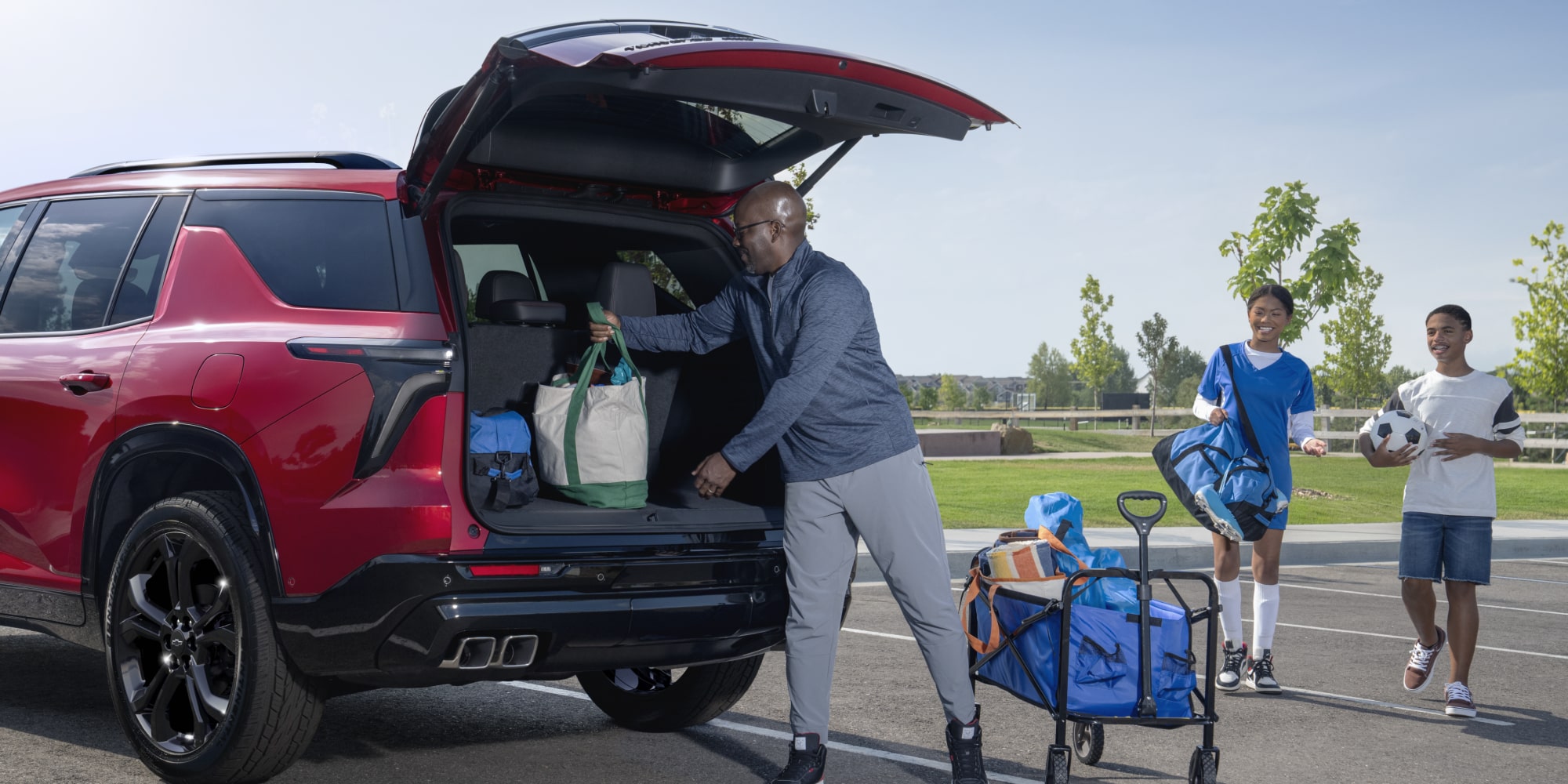 Une personne rangeant des sacs et de l’équipement dans le coffre d’une Chevrolet Traverse 2027.