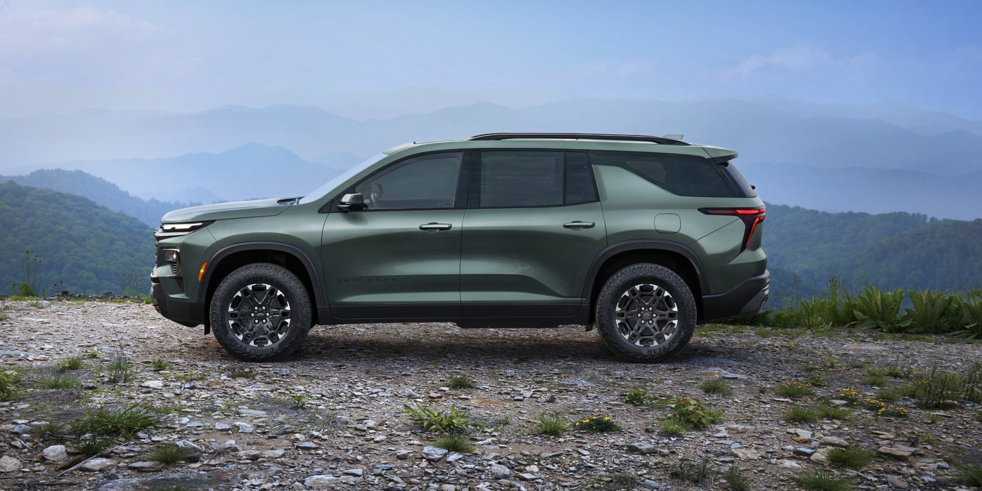 Vue latérale d’une Chevrolet Traverse 2027 stationnée sur un terrain accidenté.